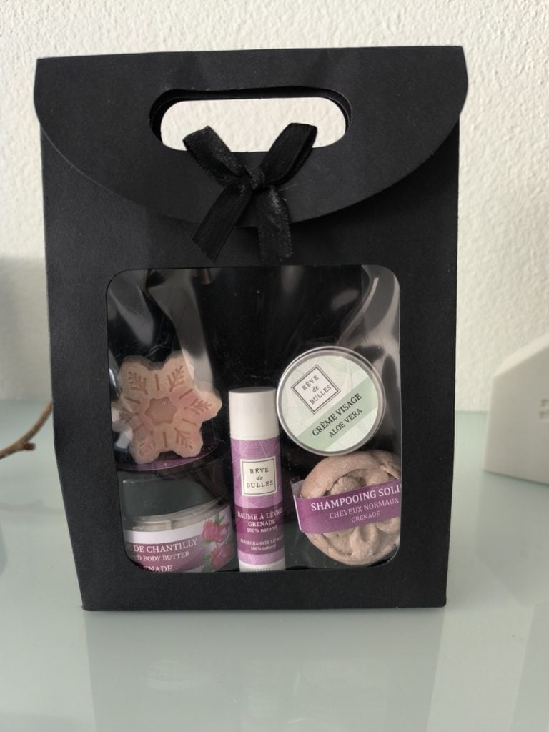 Pochette découverte des produits artisanaux Rêve de Bulles. Elle contient un stick à lèvre, un savon, un shampooing solide et une crème corporelle fondante au parfum naturel de grenade ainsi qu'une crème visage à l'aloé vera.